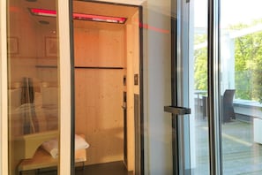 A modern bathroom with a wooden door, a glass shower enclosure, and a visible outdoor deck area. - Baltic Cloud at Villa Augustine (Ostseebad Binz)