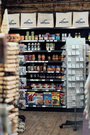 A grocery store aisle with various food products and a display of John Fowler holiday bags.