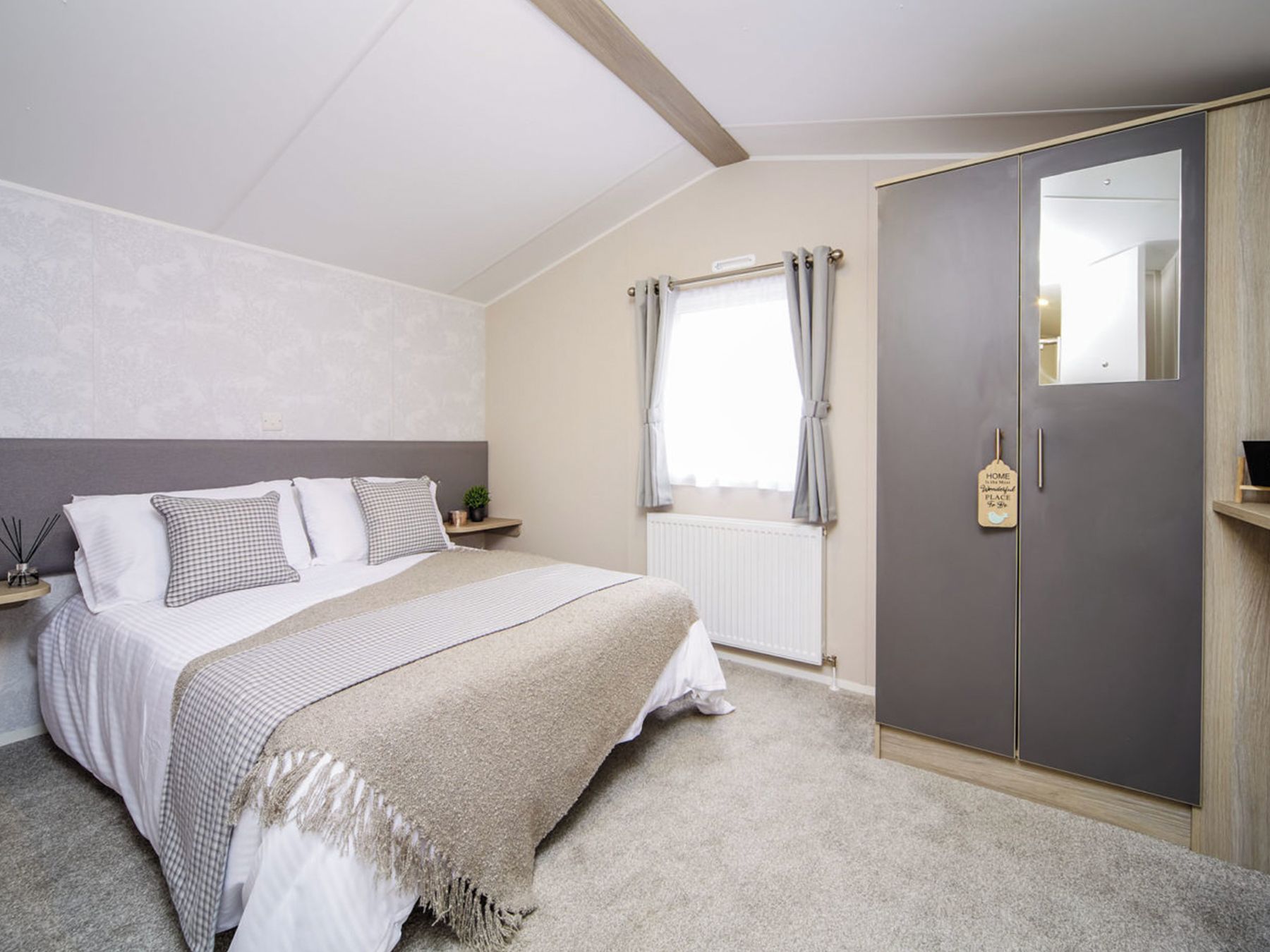 A bedroom with a bed, a wardrobe, a window with curtains, and a radiator.