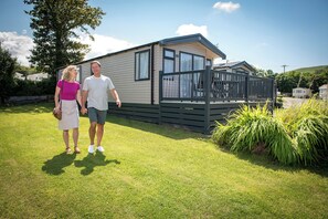 A mobile home with a deck and a fenced yard.