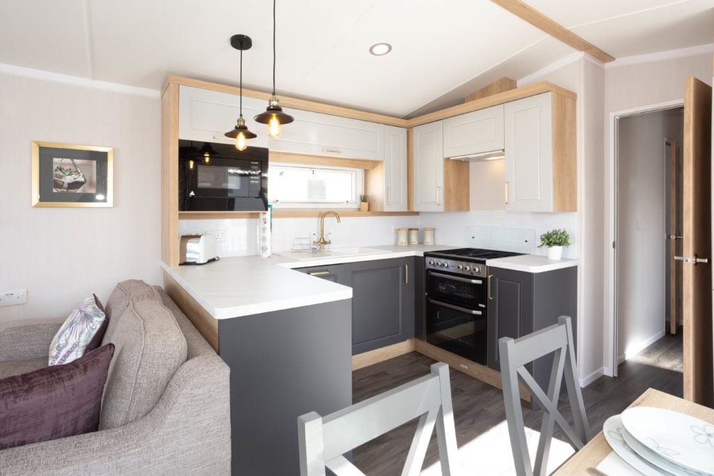 Una cocina moderna con una isla central, electrodomésticos integrados e iluminación colgante.