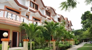 A multi-story hotel with balconies, surrounded by lush greenery and palm trees. - Cordova Home Village (Cordova)