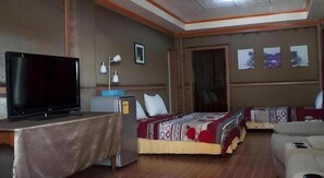 A hotel room with a bed, a television, a desk, and a sofa. - Cordova Home Village (Cordova)