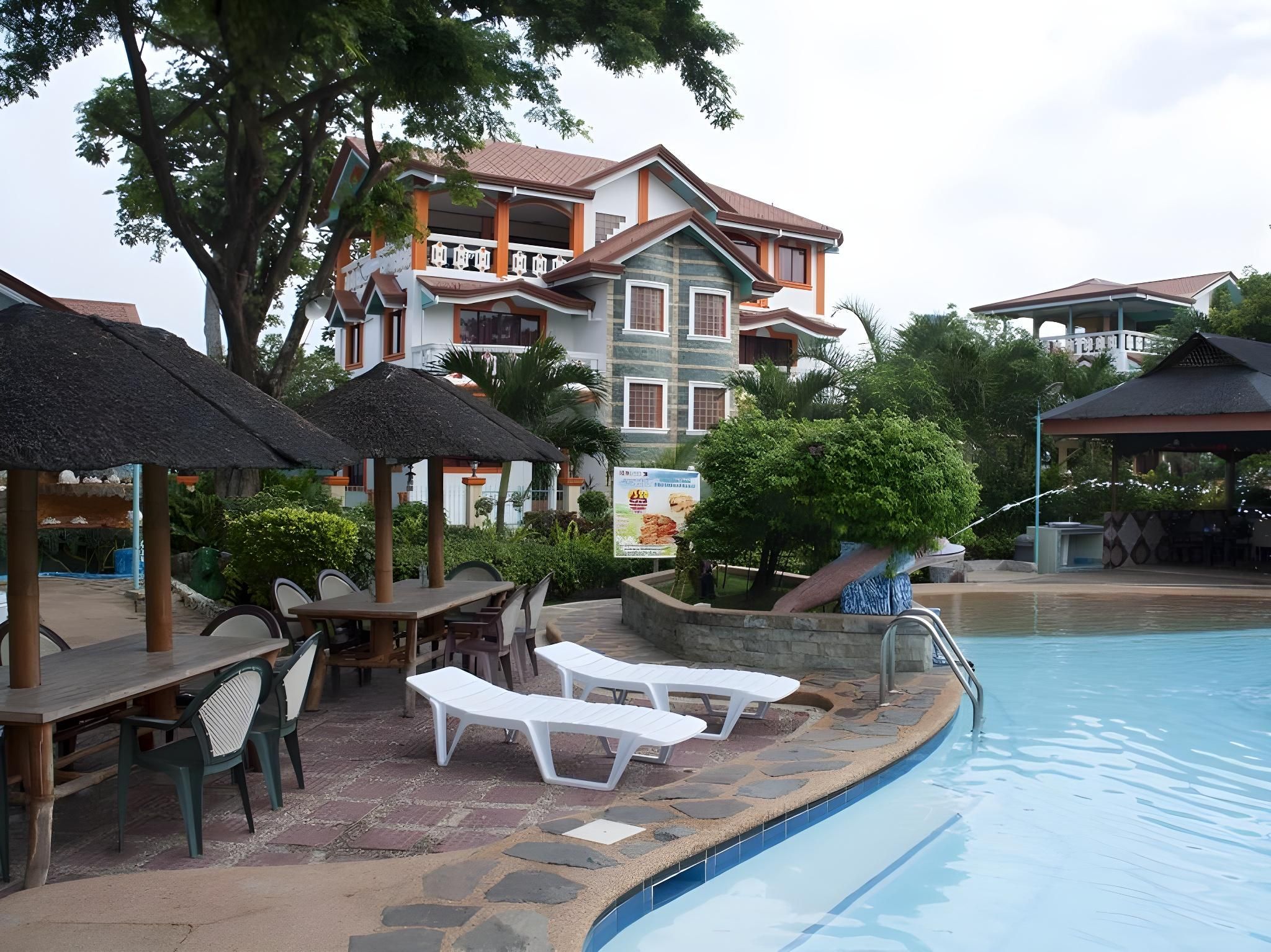 A resort with a swimming pool, lounge chairs, and a restaurant area.