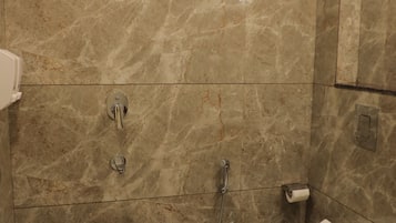 Un baño con ducha, inodoro, bidé y una escoba.
