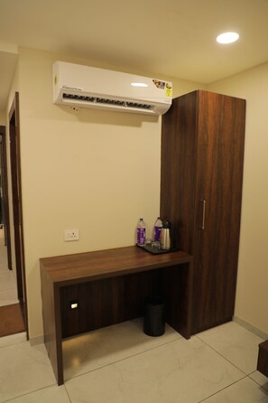 A room with a wooden desk, an air conditioning unit, a wardrobe, and a trash bin. - Hotel Lakshmi Tara (Ujjain)