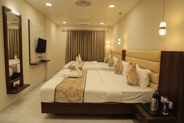 A hotel room with a large bed, a television mounted on the wall, and a mirror. - Hotel Lakshmi Tara (Ujjain)