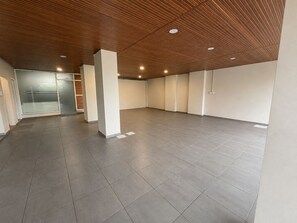 Une pièce spacieuse avec un plafond en bois, un éclairage encastré et un sol carrelé.