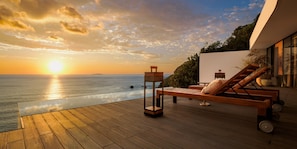 A wooden deck with a glass infinity pool overlooking the sea at sunset. - UMITO ATAMI THE SALON (Atami)