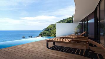 Terraza de madera con piscina y vistas al paisaje costero.