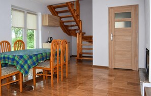 A dining area with a table set for four, wooden chairs, a staircase, and a door with a frosted glass panel. - 2 bedroom awesome home in Oslonka (Oslonka)