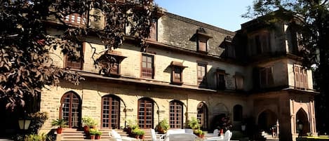 A historic building with arched windows and a courtyard with outdoor seating.