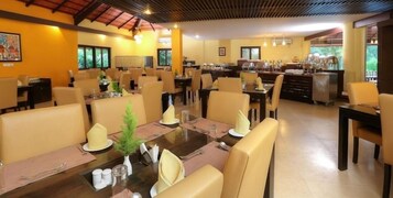 Un comedor amplio con varias mesas y sillas, una zona de bar central, y vistas al exterior.