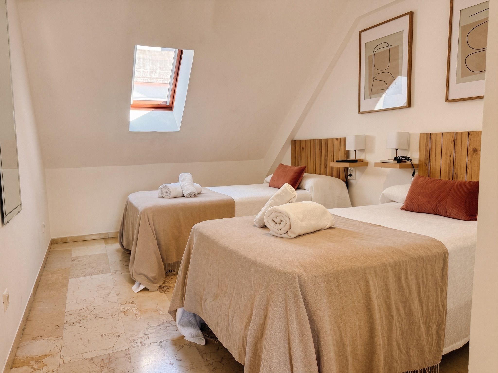 Ein Hotelzimmer mit zwei Betten, einem Oberlicht und einem Holzkopfende.