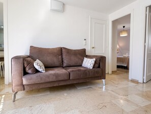 Ein braunes Sofa mit gemusterten Kissen in einem Raum mit weißen Wänden und einem Marmorboden.