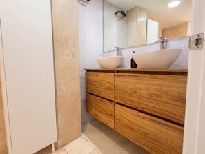 Ein modernes Badezimmer mit zwei Waschbecken, Holzschränken und einem großen Spiegel.
