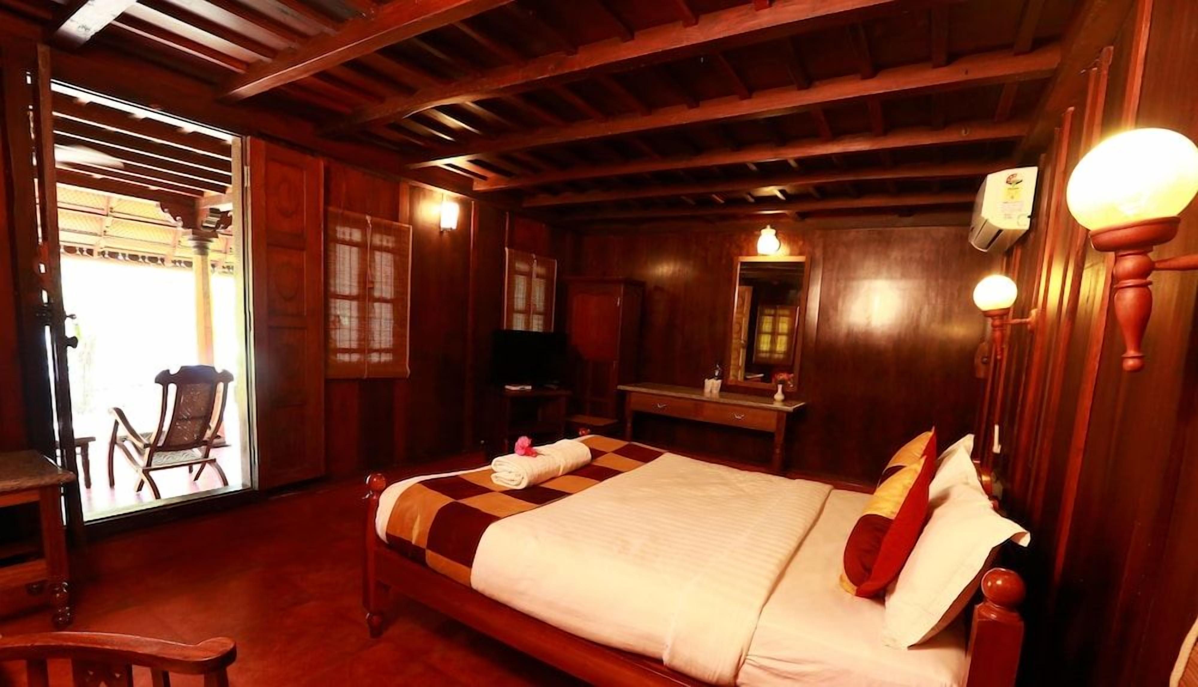 A traditional wooden room with a bed, a desk, and a chair.