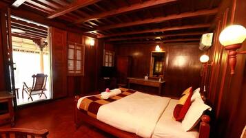 A traditional wooden room with a bed, a desk, and a chair.