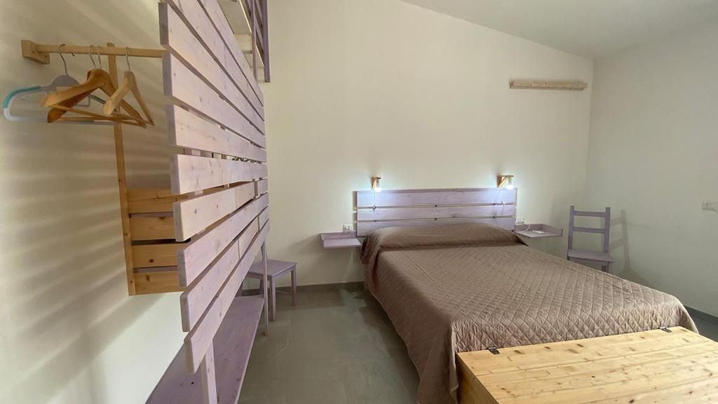 A bedroom with a bed, bedside tables, a wooden bench, and a wall-mounted rack.