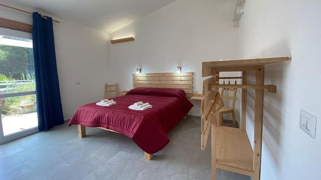 A bedroom with a bed, a wooden headboard, a table, and a chair.