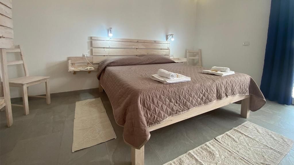 A bedroom with a wooden bed, bedside tables, a chair, and a large window with curtains.