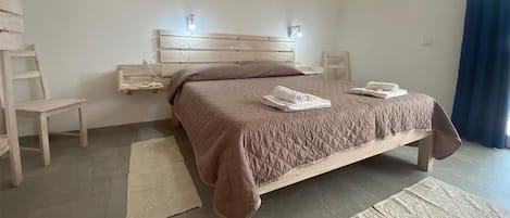A bedroom with a wooden bed, bedside tables, a chair, and a large window with curtains.
