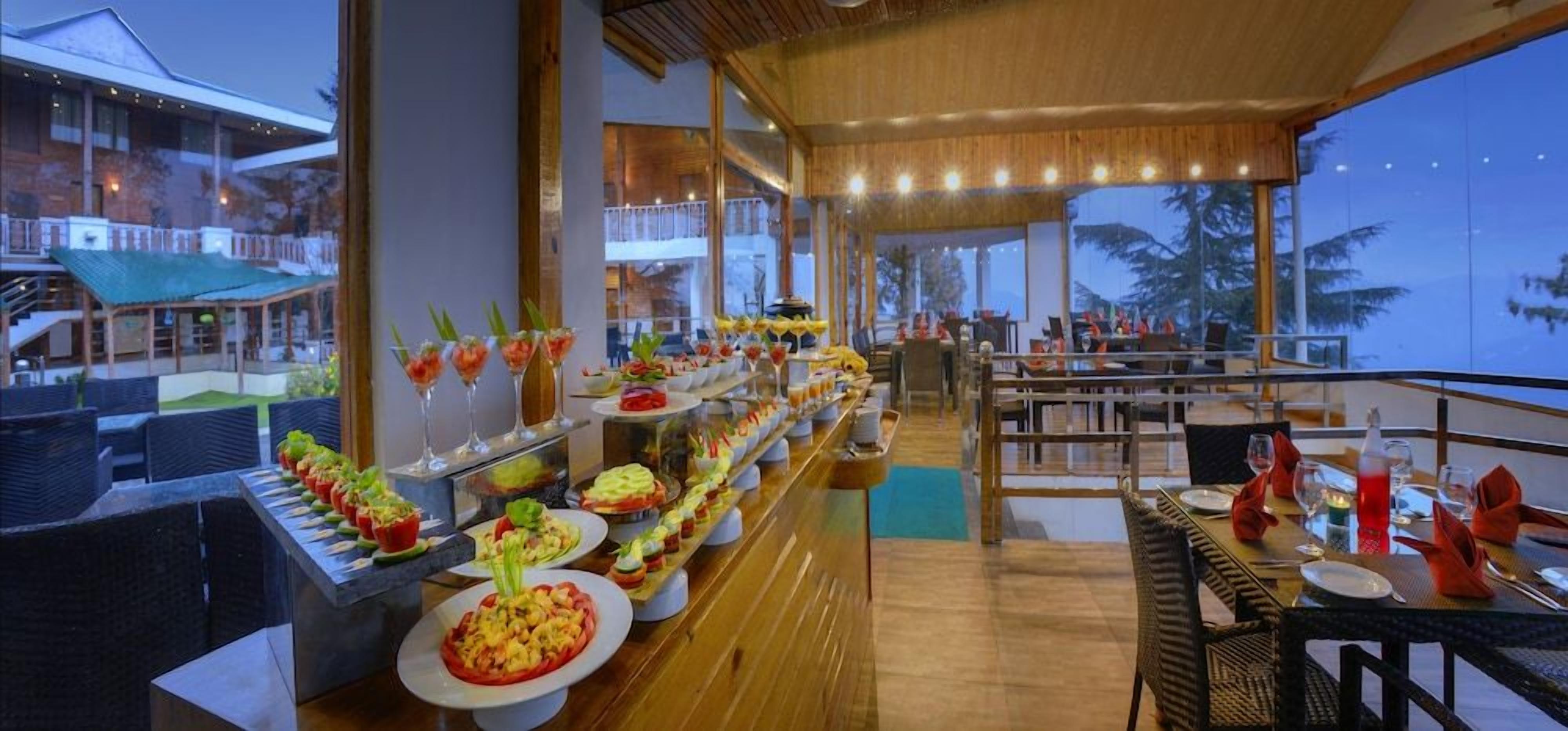 Un buffet proposant une variété de plats et de boissons, un sol en bois et une vue sur l’extérieur.