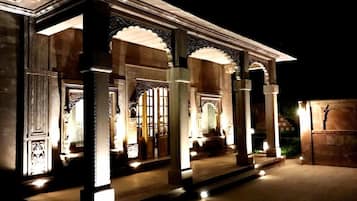 A building with ornate columns and arches, illuminated by artificial lighting.