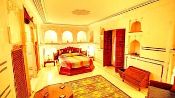 A traditional room with a large bed, a wooden cabinet, and a small table.