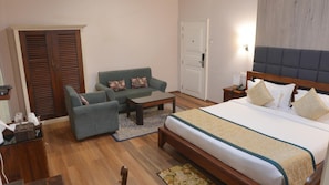 A hotel room with a bed, a sofa, a coffee table, a nightstand, and a wardrobe. - Royal Heritage-tripura Castle (Shillong)