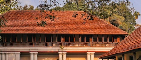 A traditional building with a tiled roof, columns, and a balcony.