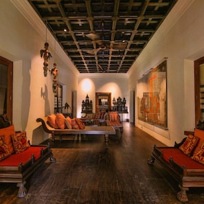 Una stanza con soffitto alto, decorazioni elaborate sul soffitto, un divano con cuscini a fantasia, un tavolo e un'ampia opera d'arte incorniciata appesa al muro.