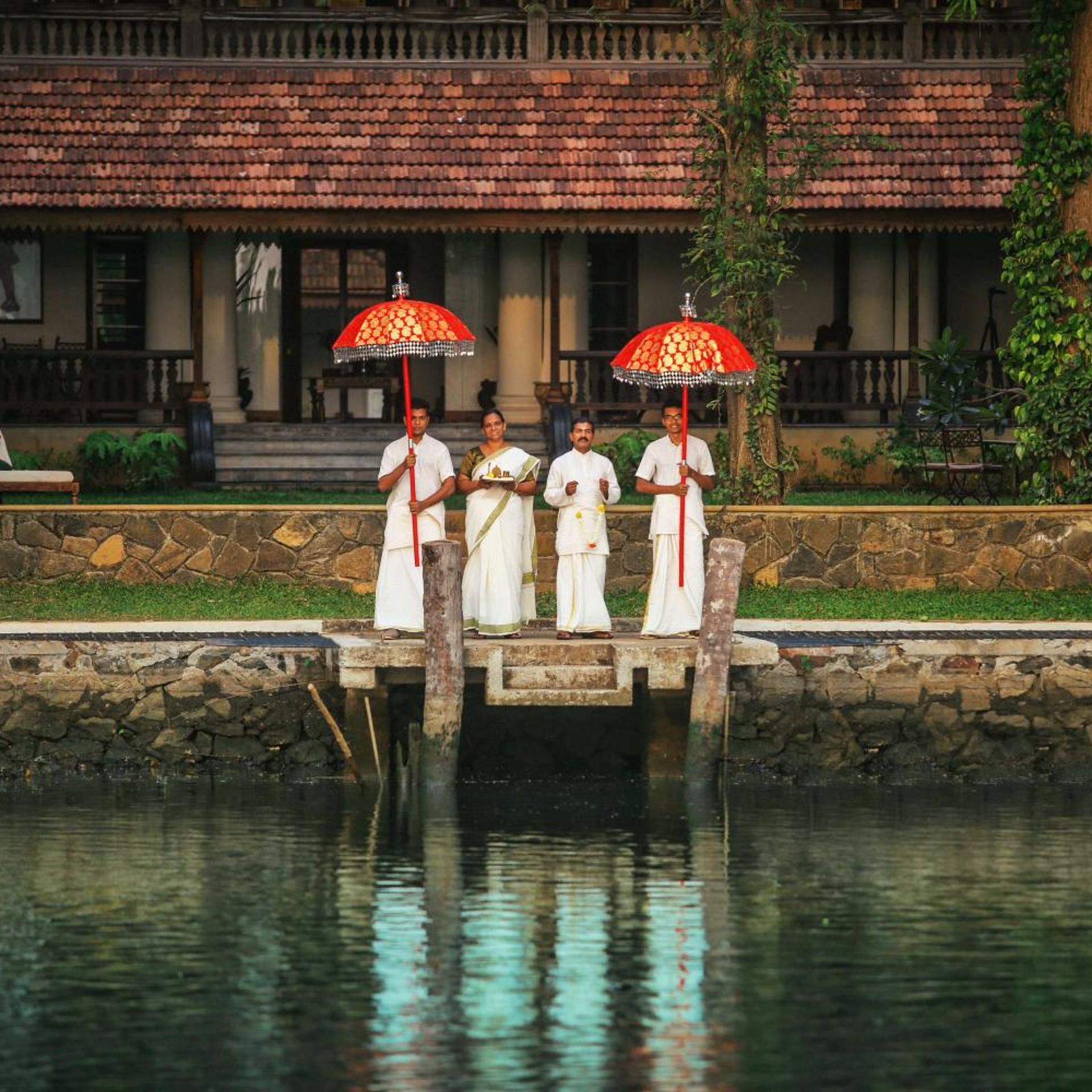 A group of people standing on a stone bridge over a body of water, with a building in the background.