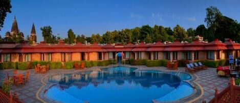 Un hotel con piscina, mobiliario exterior y arquitectura tradicional.