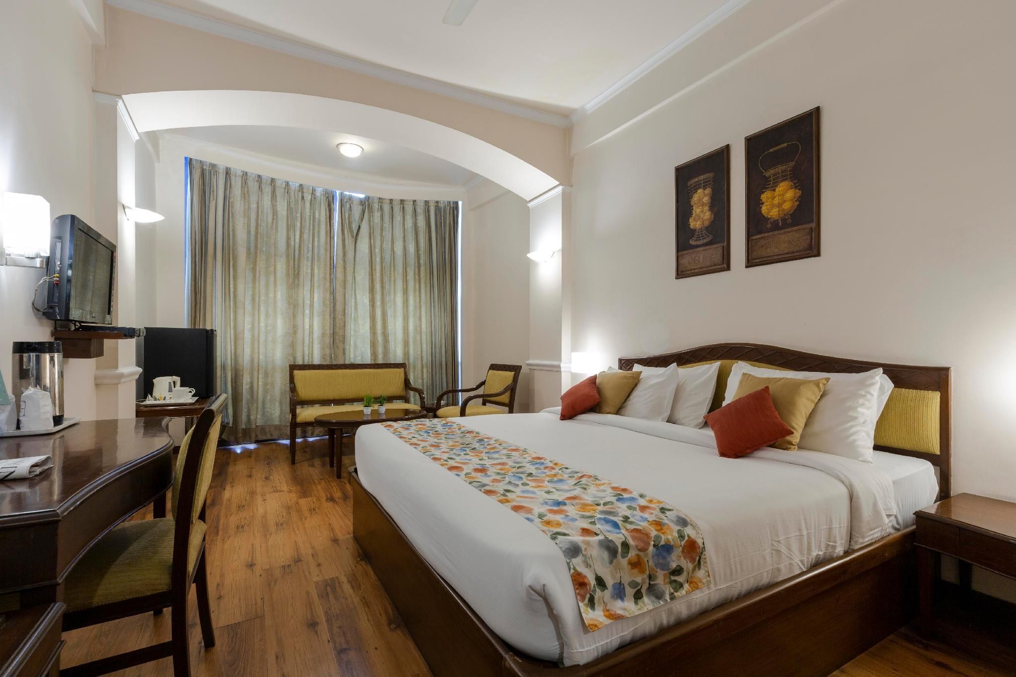 Une chambre d’hôtel avec un lit, un bureau, une chaise et des rideaux.