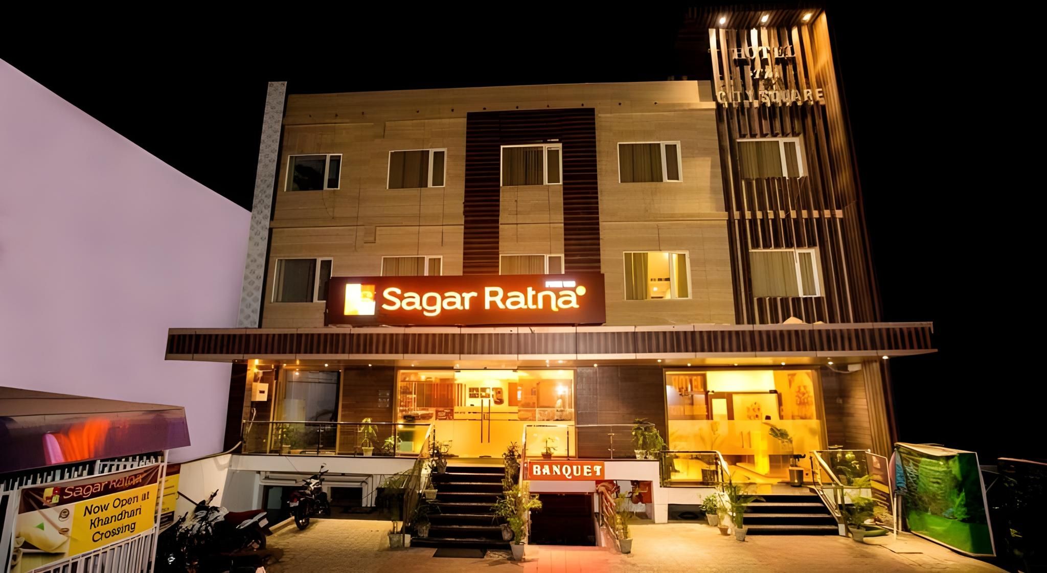 A hotel with a prominent sign for 'Sagar Ratna' and a visible entrance with steps leading to the door.