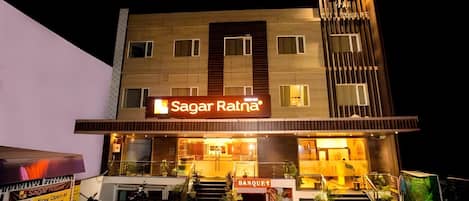 Ett hotell med en tydlig skylt som visar namnet ”Sagar Ratna” och en väl synlig entré med trappsteg som leder upp till dörren.