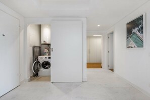 A hallway with a laundry area, a door leading to another room, and a framed picture on the wall. - Holiday apartment with 2 bedrooms (Funchal)