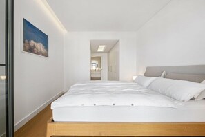 A minimalist bedroom with a bed, a painting, and a view into the bathroom. - Holiday apartment with 2 bedrooms (Funchal)