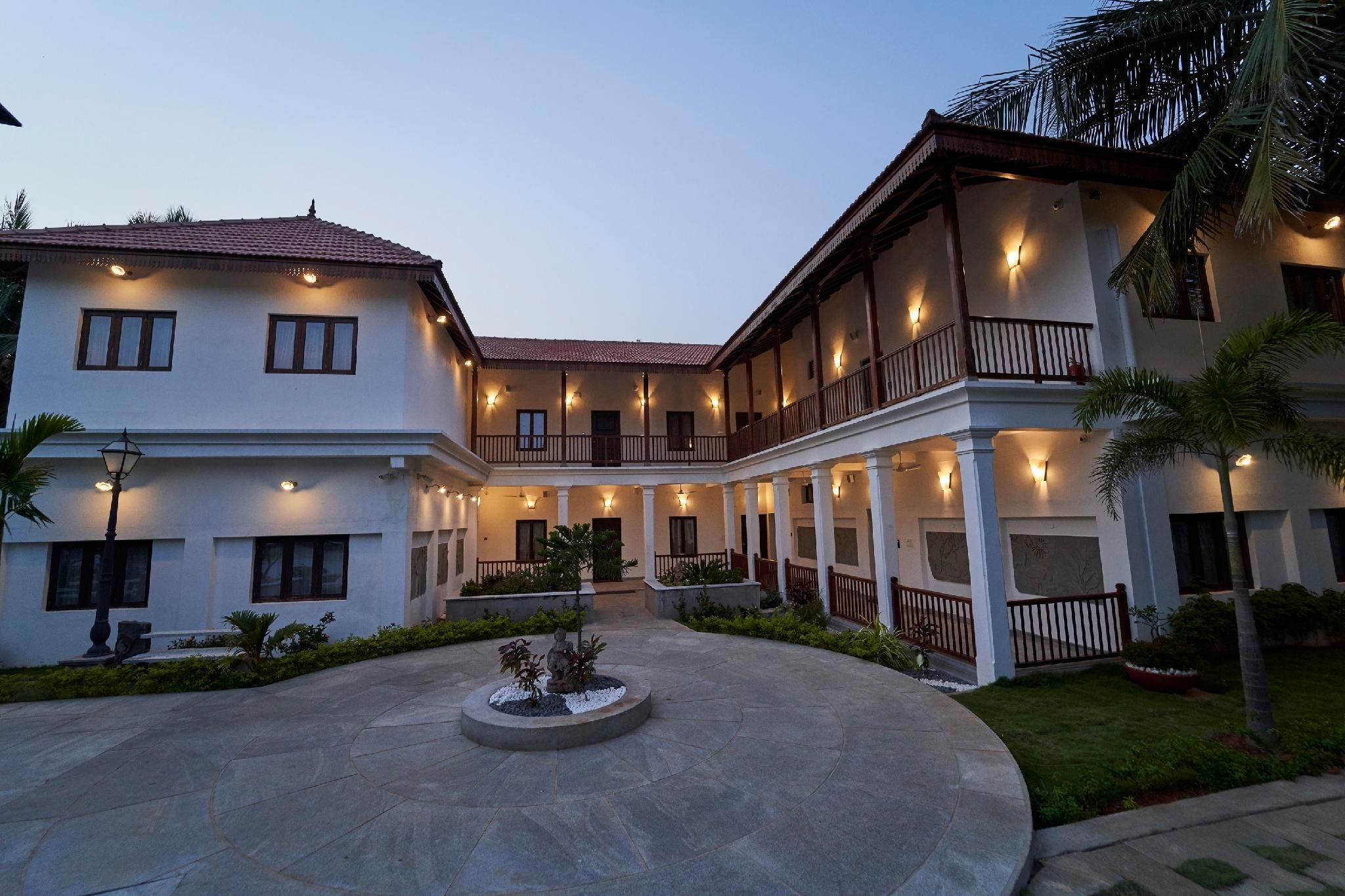 A two-story building with a courtyard, featuring a central fountain and multiple balconies with lighting.