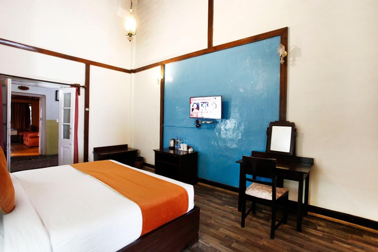 A hotel room with a bed, a television, a desk, and a chair.