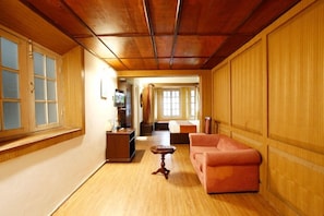 A room with a wooden ceiling, a sofa, a small table, a bed, and a television. - Palace Belvedere (Nainital)