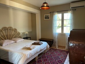 Une chambre à coucher avec un lit, une lampe de chevet, une fenêtre avec des rideaux et un climatiseur fixé au mur.