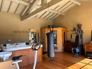 Une salle de sport équipée d’un vélo d’appartement, d’un sac de frappe et d’une machine de musculation.