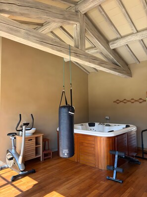 A room with a wooden ceiling, a wooden floor, a massage table, a massage chair, and a stationary bike. - Holiday Home 'Beautiful Haven Of Peace' with Private Pool, Wi-Fi and Air Conditioning (Mas-Blanc-des-Alpilles)