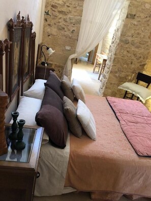 Un dormitorio con cama, almohadas, mesita de noche y lámpara.