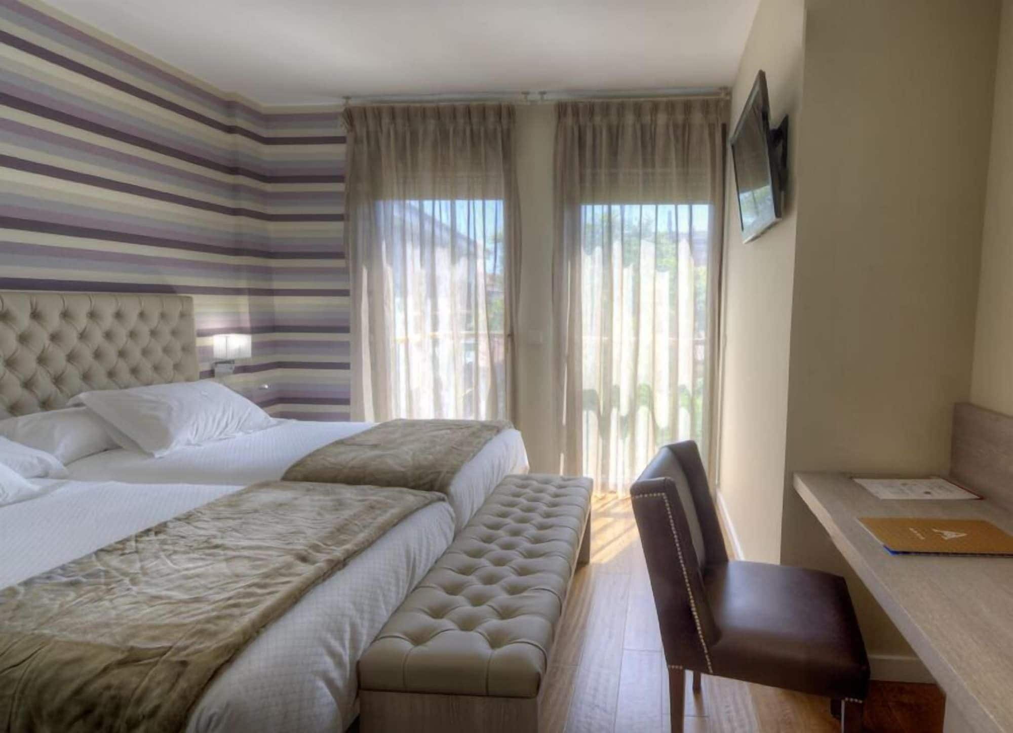 Una habitación de hotel con una cama grande, un banco, un escritorio y un televisor.