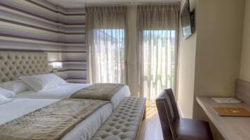 Una habitación de hotel con una cama grande, un banco, un escritorio y un televisor.