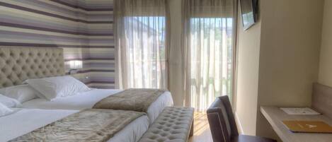 Una habitación de hotel con una cama grande, un banco, un escritorio y un televisor.