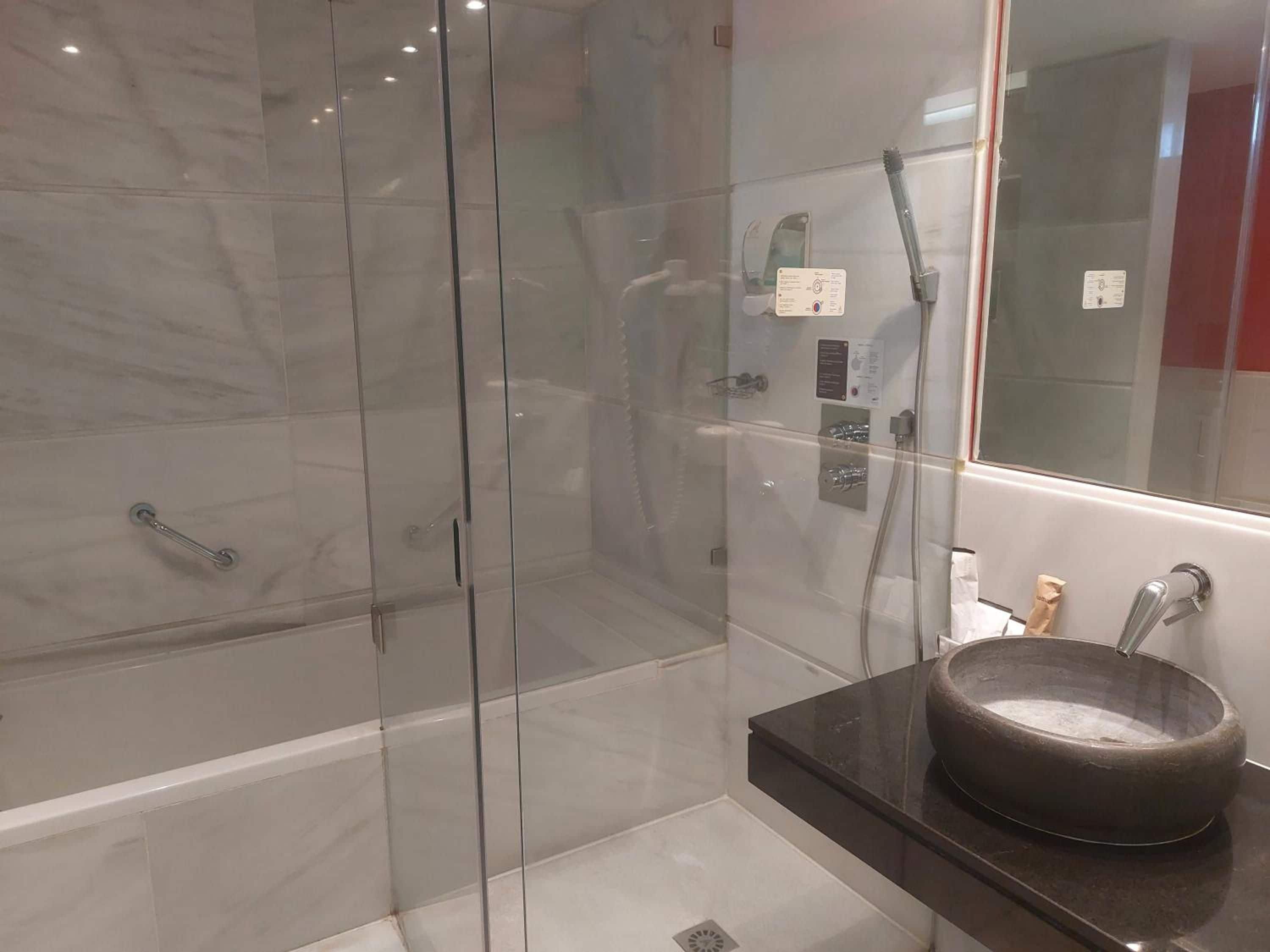 A modern bathroom with a glass-enclosed shower, a black countertop, and a round basin.